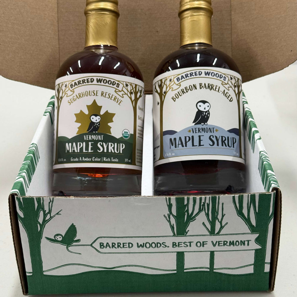 
                  
                    Two bottles of Barred Woods maple syrup in a branded box on a white surface.
                  
                