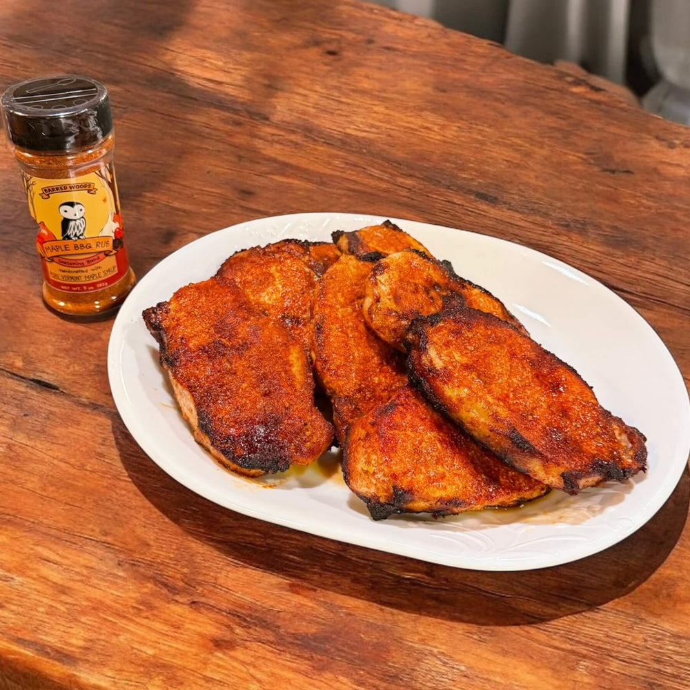 
                  
                    Plated barbecue pork  on a wooden table with a bottle of  Barred Woods Maple Sugar Barbeque Rub.
                  
                